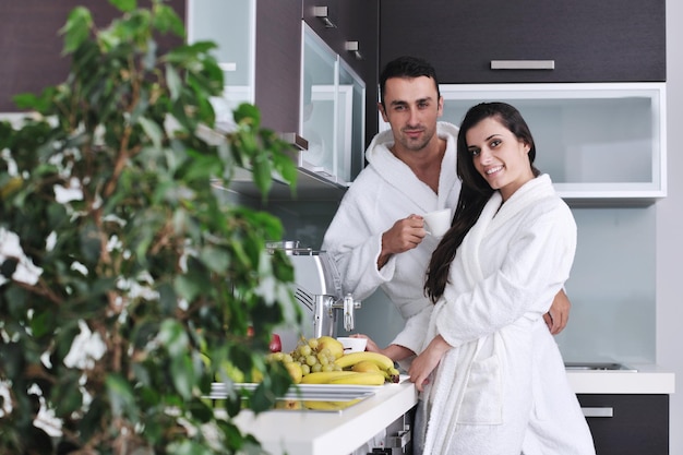 Jovem casal apaixonado tomando uma xícara de café fresco da manhã no apartamento moderno