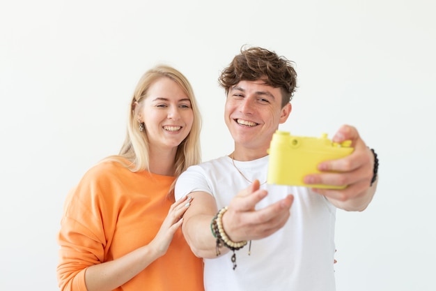 Jovem casal apaixonado, um homem fofo e uma mulher encantadora fazendo selfie na câmera de filme amarelo vintage