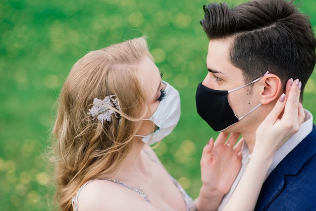 Jovem casal apaixonado usando máscaras no dia do casamento