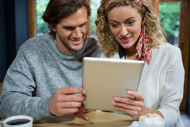 Jovem casal apaixonado usando um tablet na mesa do refeitório