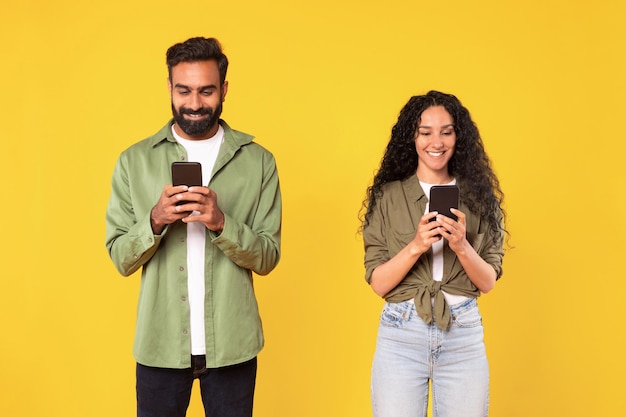 Jovem casal árabe segurando seus smartphones e conversando em estúdio on-line