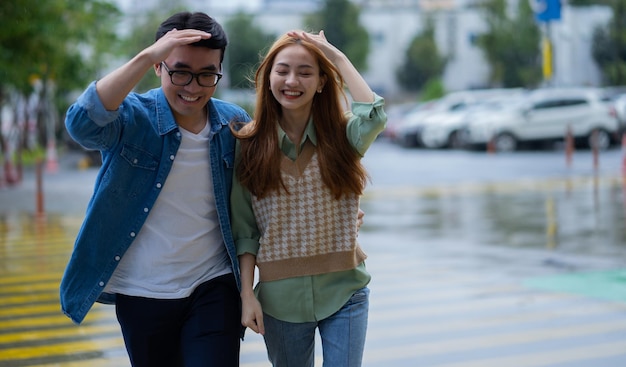 Jovem casal asiático andando na chuva