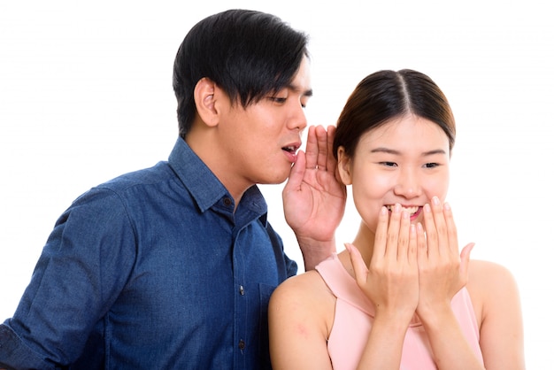 Jovem casal asiático com homem sussurrando para uma mulher rindo