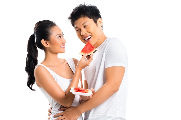 Jovem casal asiático comendo frutas e se divertindo