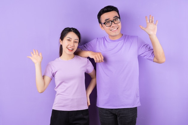 Jovem casal asiático posando em fundo roxo