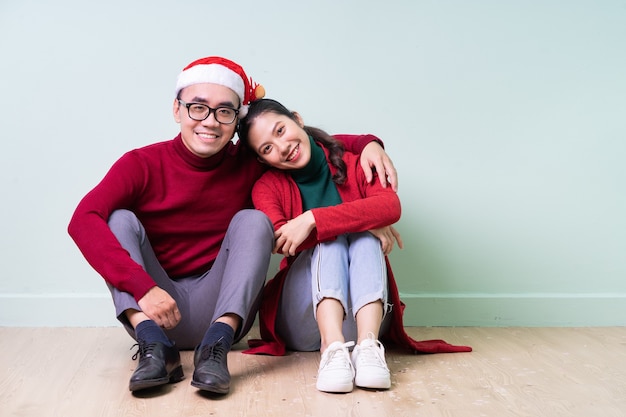 Jovem casal asiático posando em um fundo verde com o conceito de natal