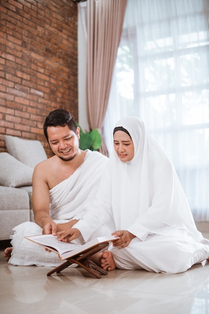 Jovem casal asiático rezando com Al-Qur'an e contas de oração