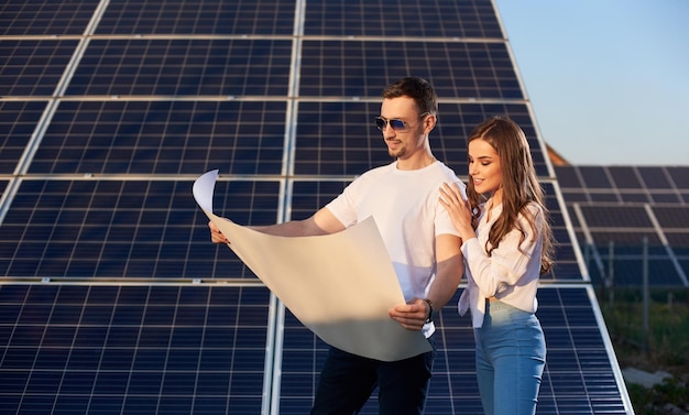 Foto jovem casal assistindo a um plano de fundo de painéis solares