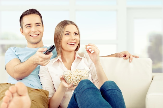 Jovem casal assistindo TV em casa