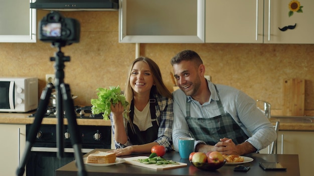 Jovem casal atraente filmando blog de comida de vídeo sobre cozinhar na câmera dslr na cozinha