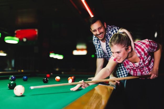 Jovem casal atraente jogando sinuca em bar