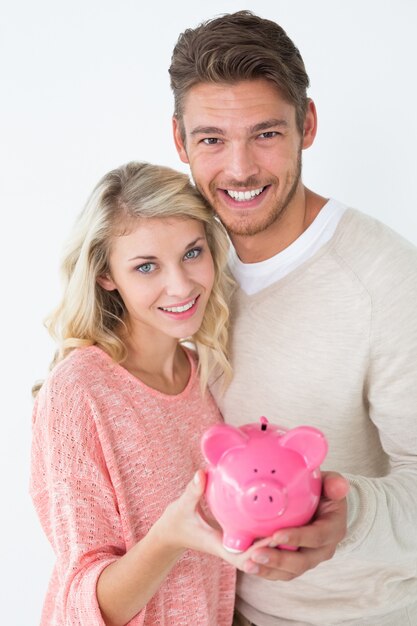 Foto jovem casal atraente segurando piggybank