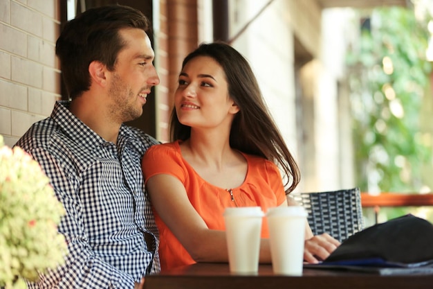 Jovem casal bebe café no café ao ar livre