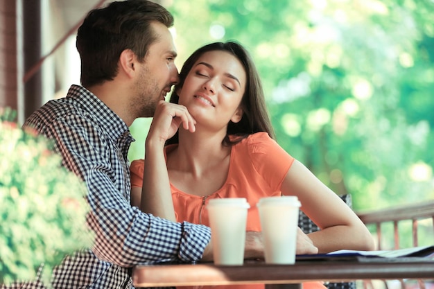 Jovem casal bebe café no café ao ar livre