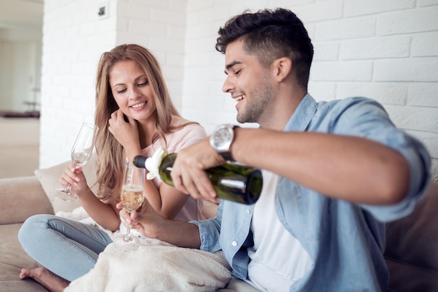 Jovem casal bebe vinho em sua sala de estar