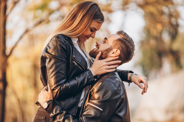 Jovem casal beijando no parque outonal. Um homem levantou sua mulher nos braços