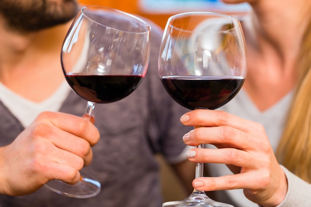 Jovem casal bonito beber vinho tinto em casa