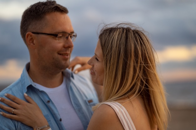 Jovem casal bonito caucasiano feliz no pôr do sol na praia no verão.