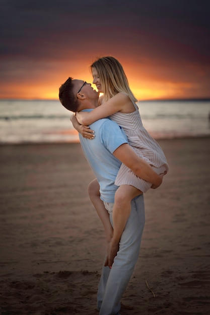 Jovem casal bonito caucasiano feliz no pôr do sol na praia no verão.