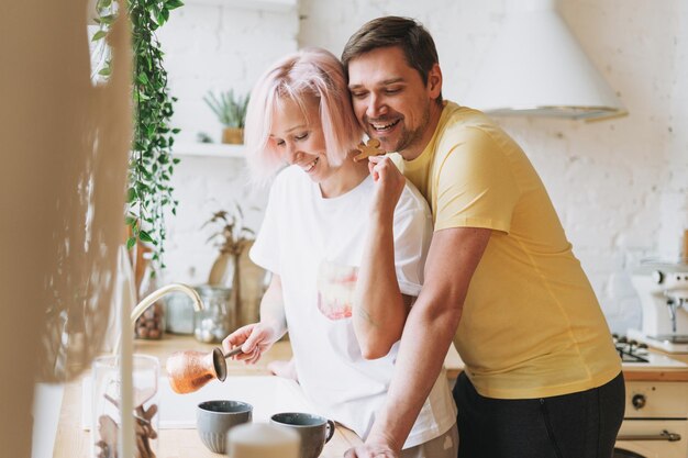 Foto jovem casal bonito família feliz se divertindo com café da manhã na cozinha brilhante em casa