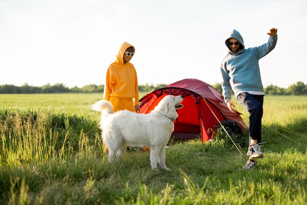 Jovem casal brinca com seu cachorro no acampamento