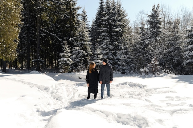 Jovem casal brincando enquanto caminhava no inverno perto da floresta um plano geral de um casal apaixonado contra o pano de fundo da natureza do inverno