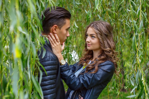 Jovem casal casual gosta um do outro sob a árvore verde.