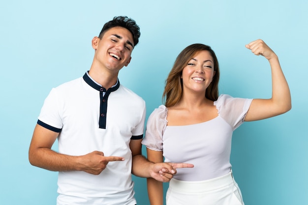 Jovem casal caucasiano em azul fazendo um gesto forte