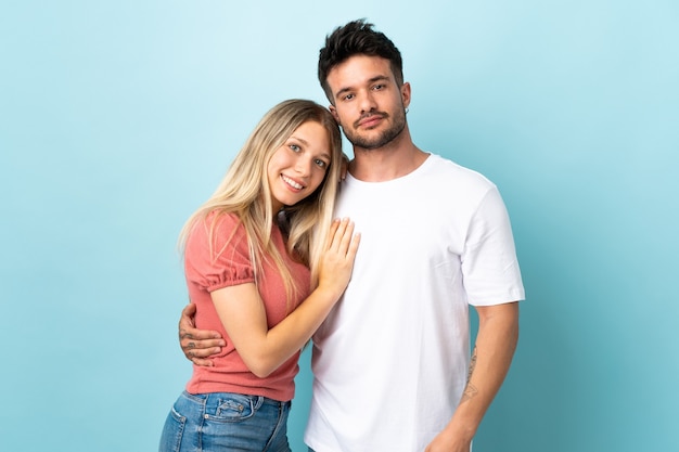 Jovem casal caucasiano isolado em um fundo azul rindo