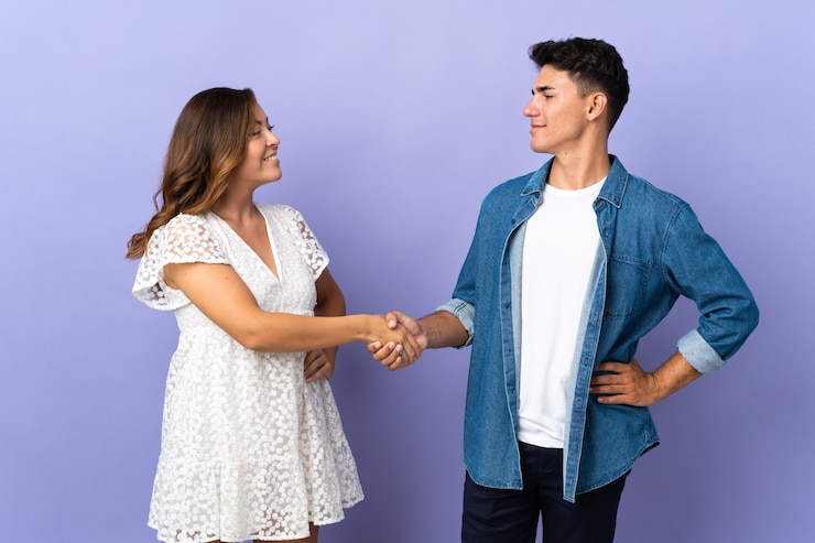 Foto jovem casal caucasiano num aperto de mão roxo após um bom negócio