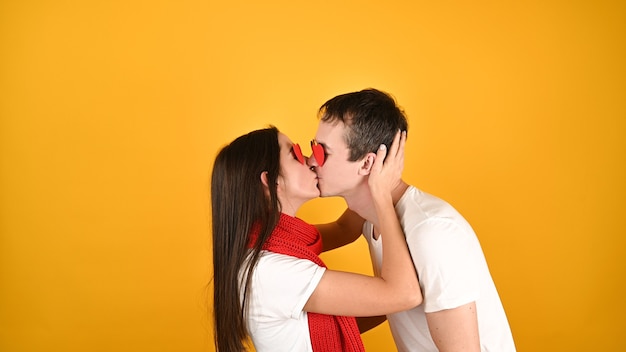 Jovem casal caucasiano se beijando e se abraçando em amarelo