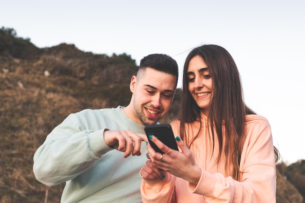 Jovem casal caucasiano usando um smartphone na natureza