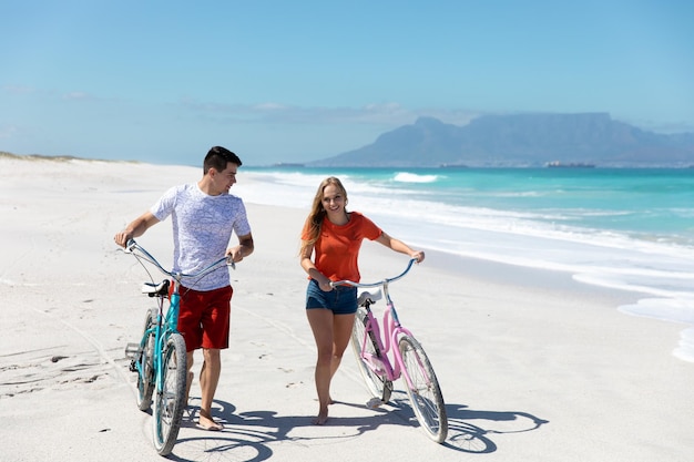 Jovem casal com bicicletas na praia