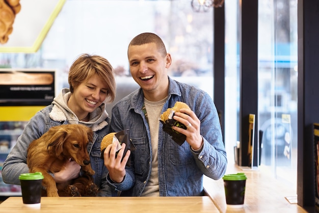 Jovem casal com cachorro almoçando fast food