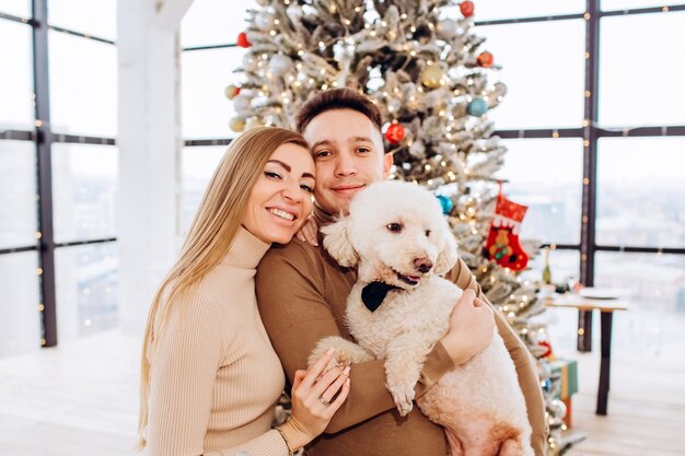 Jovem casal com cachorro e árvore de Natal,