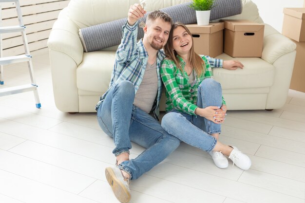 Jovem casal com caixas e segurando chaves planas.