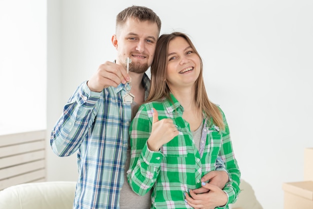 Jovem casal com caixas e segurando chaves planas