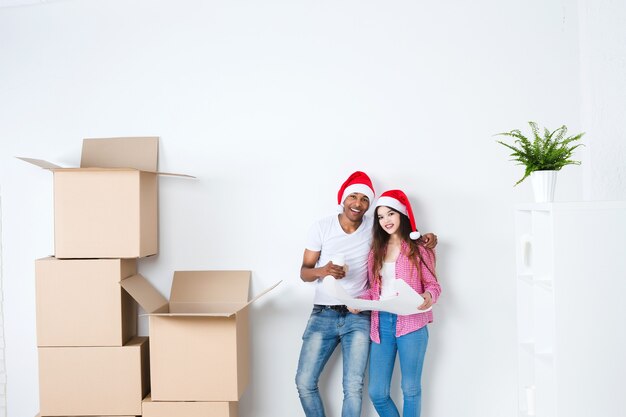 Jovem casal com chapéu de Papai Noel em casa nova