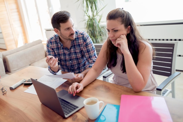 Jovem casal com contas e laptop