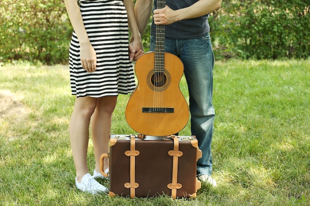 Jovem casal com mala vintage e guitarra ao ar livre