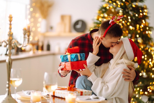 Jovem casal com presentes de Natal em casa perto da árvore de Natal Dia romântico Feriados Ano Novo