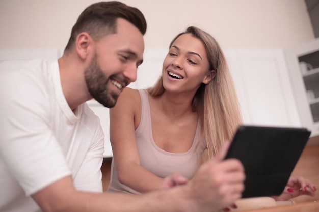 Jovem casal com tablet digital sentado na cozinha