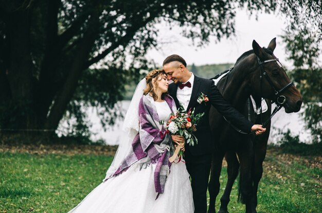 Jovem casal com um cavalo preto no parque