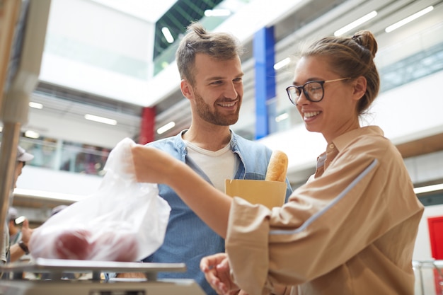 Jovem casal comprando legumes no supermercado