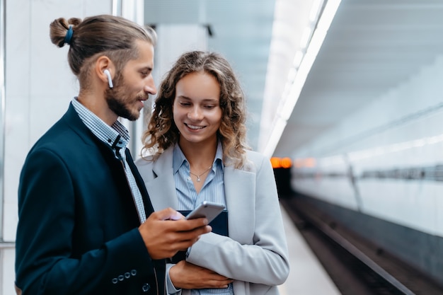 Jovem casal conversando em pé na plataforma do metrô