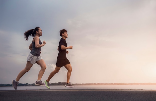 Foto jovem casal correndo na rua para fazer exercícios com uma bela luz