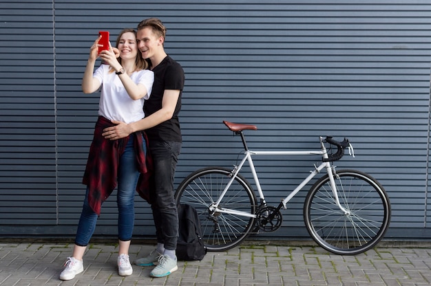 Jovem casal dançando com uma bicicleta no contexto da parede