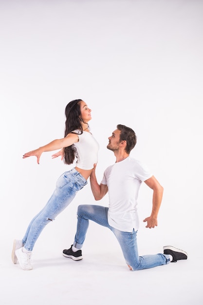 Jovem casal dançando dança social latina bachata, merengue, salsa. dois pose de elegância em fundo branco.