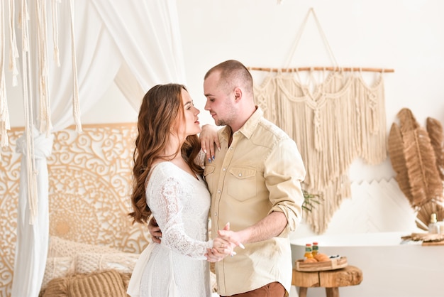 Jovem casal dançando em um fundo lindo quarto branco.