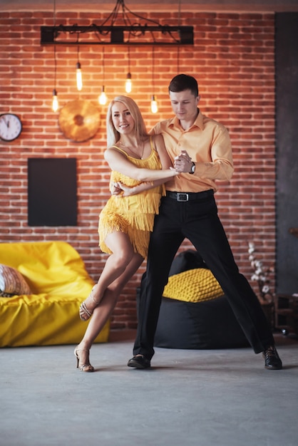 Jovem casal dançando música latina: Bachata, merengue, salsa. Pose de duas elegância no café com paredes de tijolo